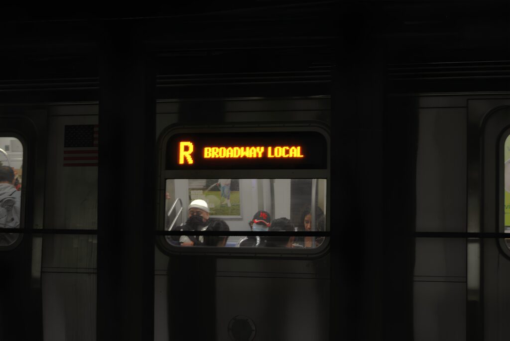 Homme assis dans le métro, photographé par la fenêtre du wagon.